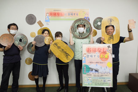 (写真)貨幣パネルを持つ博物館スタッフの写真