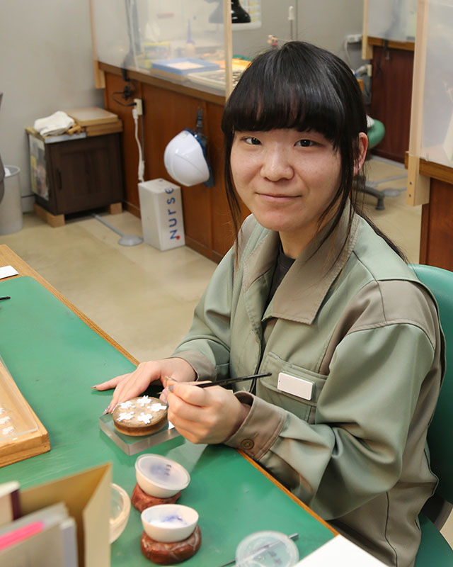勲章の素材に七宝釉薬の盛り付けをしている職員の写真